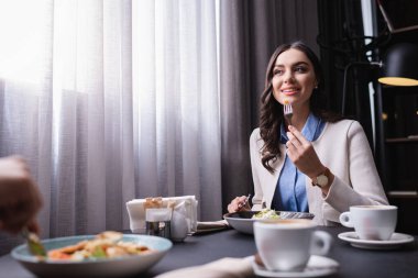 Restoranda erkek arkadaşıyla yemek yiyen, gülümseyen bir kadın. 