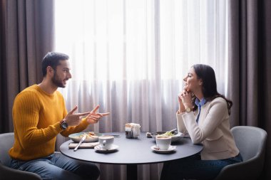 Restoranda yemek yerken gülümseyen kız arkadaşını gösteren Arap bir adam. 