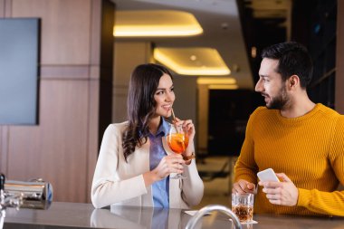 İçkili ve akıllı telefonlu neşeli çok kültürlü arkadaşlar restoranda vakit geçiriyorlar. 