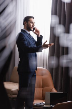 Restoranda laptopların yanında akıllı telefondan konuşan Müslüman işadamı. 