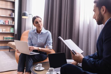 Bilgisayarlı bir iş kadını restoranda defteri olan Arap bir ortağa bakıyor. 