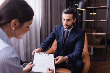 Arap işadamı iş kadınının yanında oturmuş restoranda bulanık ön planda şarkı söylüyor. 