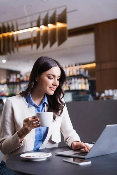 Glad Frilansare Arbetar Laptop Medan Håller Kopp Kaffe Restaurang Suddig — Stockfoto