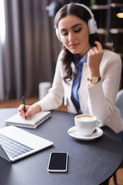 Freelancer Headphones Writing Notebook Laptop Smartphone Blank Screen Blurred Background — Stock Photo, Image