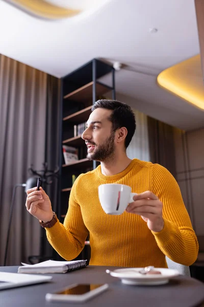Freelancer Arabian Surpreendente Segurando Xícara Café Caneta Perto Smartphone Primeiro — Fotografia de Stock