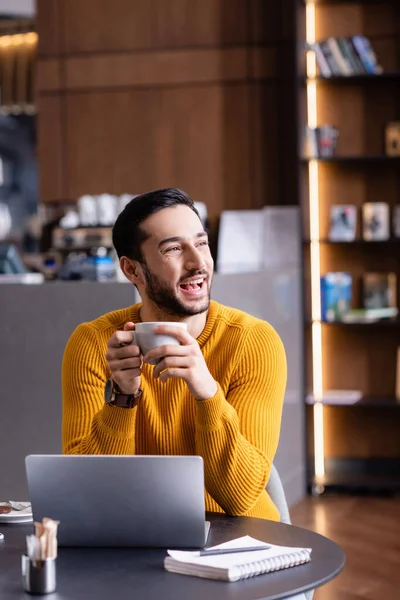 Excited Arabian Freelancer Laughing While Holding Cup Coffee Looking Away — Stock Photo, Image