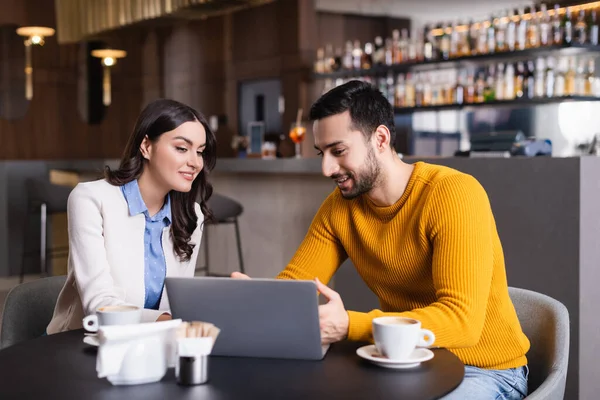 Cheerful Arabian Freelancer Pointing Laptop Smiling Woman Restaurant Blurred Foreground — Stock Photo, Image