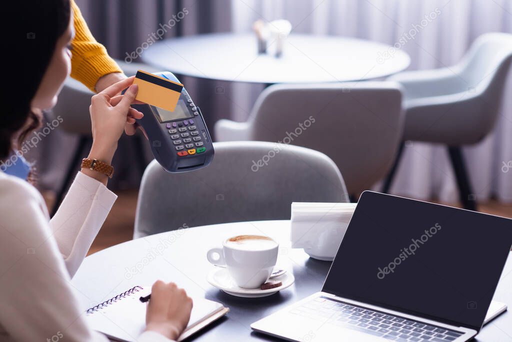 cropped view of freelancer holding credit card near credit card reader in hand of waiter