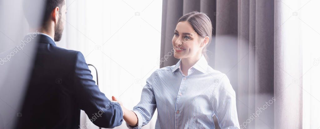 Smiling businesswoman handshaking with muslim partner in modern restaurant, banner 