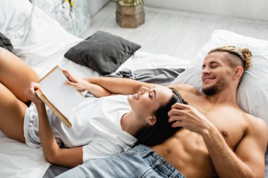 Kitapla gülümseyen kadın, seksi erkek arkadaşının yanında yatıyor. 