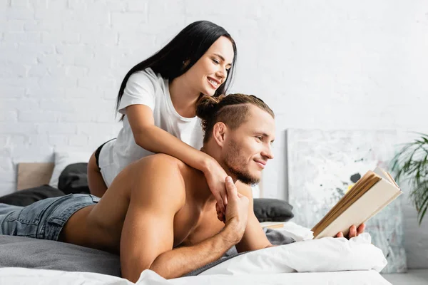 Wanita Tersenyum Memeluk Pacar Berotot Membaca Buku Tempat Tidur — Stok Foto