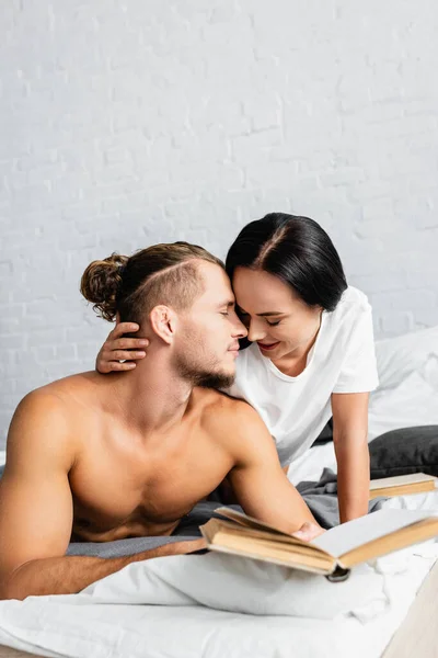 Woman Kissing Shirtless Man Book Blurred Foreground Bed — Stock Photo, Image