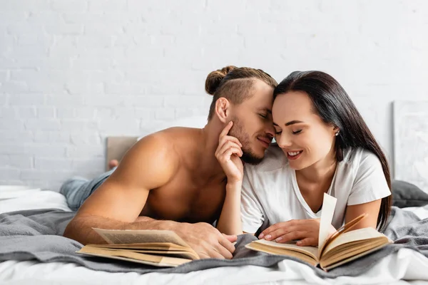 Shirtless Man Kissing Smiling Girlfriend Books Blurred Foreground — Stock Photo, Image