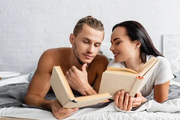 Smiling Woman Holding Book Looking Shirtless Boyfriend Bed — Stock Photo, Image