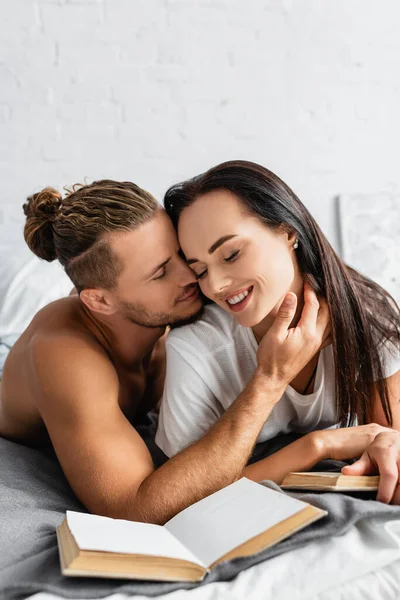 Sexy Man Touching Smiling Woman Books Blurred Foreground Bedroom — Stock Photo, Image