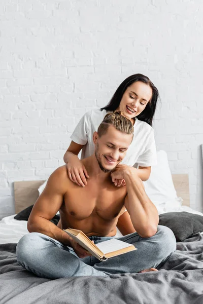 Young Woman Hugging Muscular Boyfriend Reading Book Bedroom — Stock Photo, Image