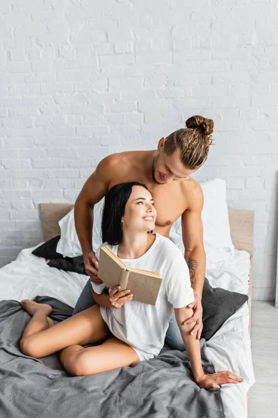 Smiling Woman Shirt Holding Book Sexy Man Bed — Stock Photo, Image