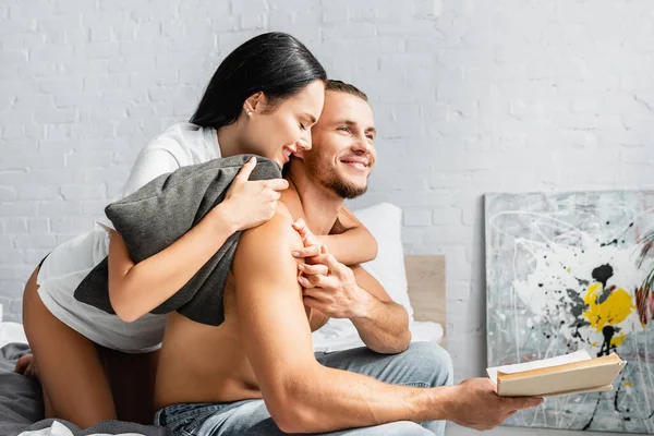 Smiling Woman Pillow Hugging Shirtless Man Book Bed — Stock Photo, Image