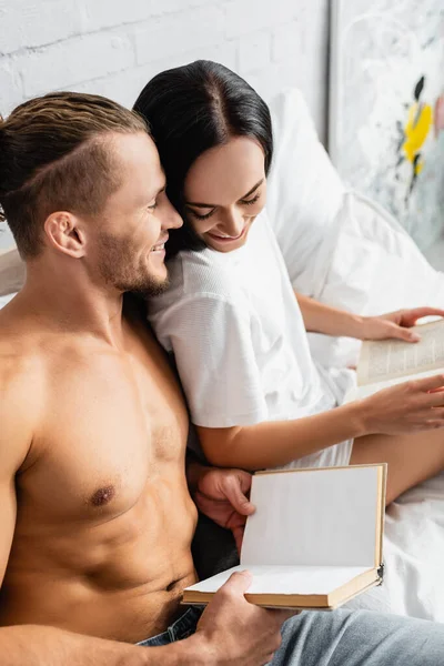 Sonriente Hombre Sin Camisa Sosteniendo Libro Cerca Novia Cama — Foto de Stock