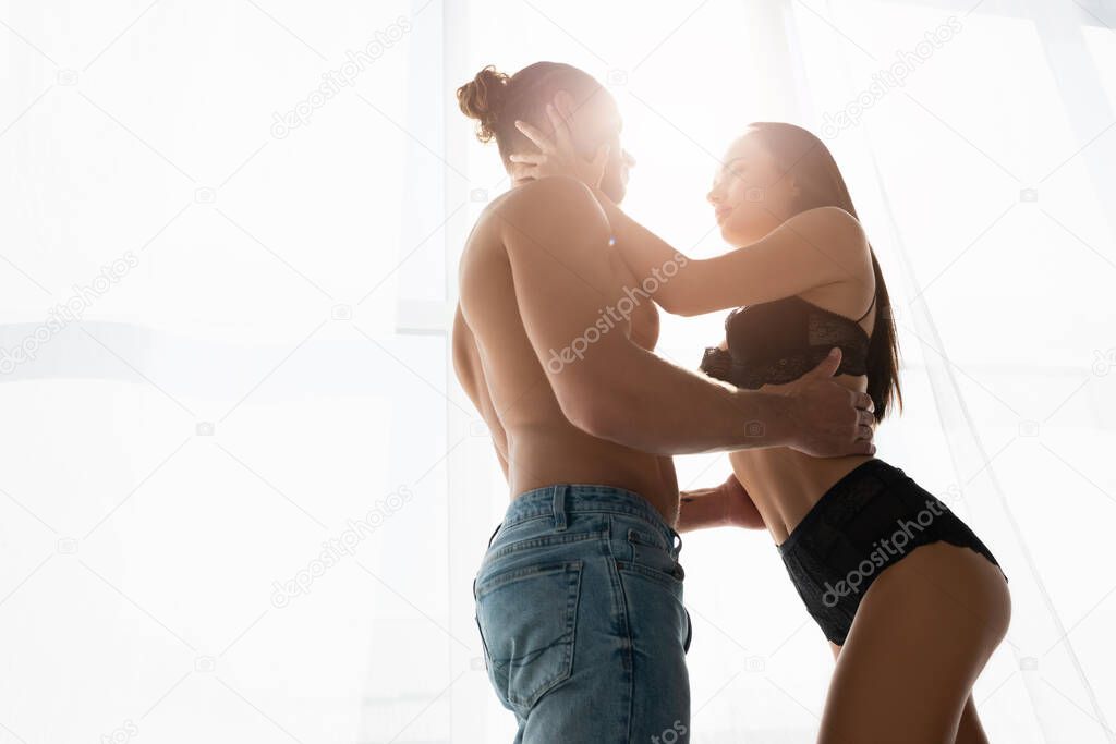 Low angle view of sexy couple touching each other near window 
