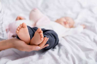 Küçük oğlunun ayaklarına dokunan bir kadın beyaz bir yatakta uyuyor, geçmişi bulanık.
