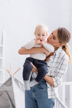 Küçük oğlunu kucağına alan genç bir anne.