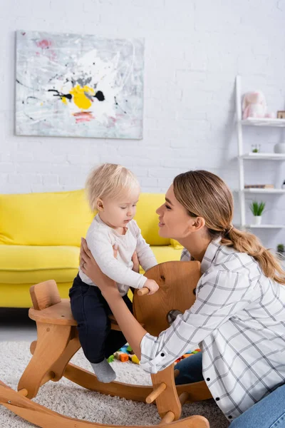 Junge Mutter Berührt Sohn Auf Schaukelpferd — Stockfoto