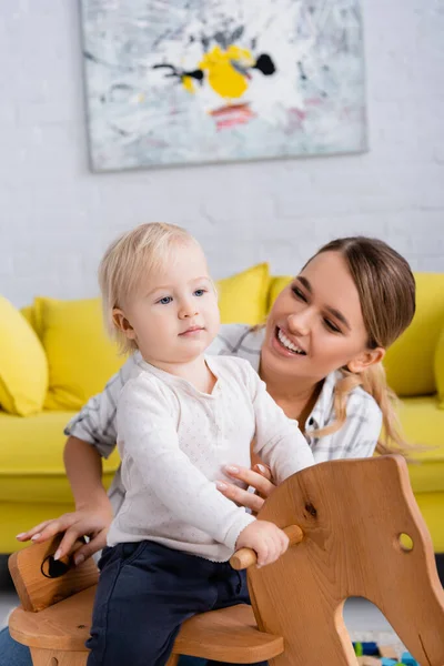 Happy Young Woman Toddler Boy Riding Rocking Horse Home — Stock Photo, Image