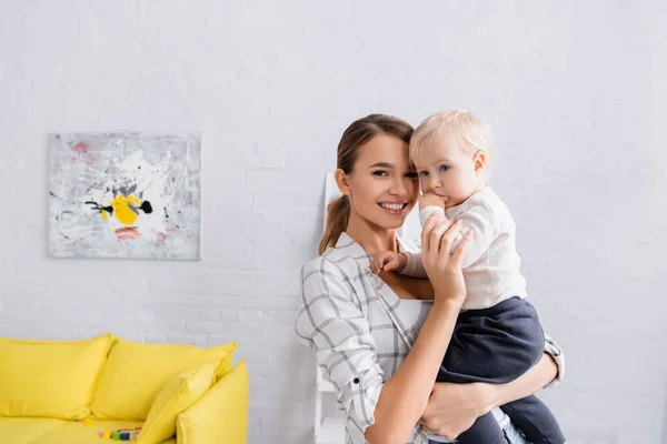 Glückliche Frau Lächelt Die Kamera Während Sie Ihren Kleinen Sohn — Stockfoto