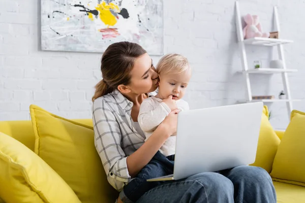 Young Freelancer Kissing Little Kid While Sitting Yellow Sofa Laptop — Stock Photo, Image