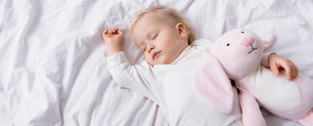 overhead view of little child sleeping with toy bunny, banner