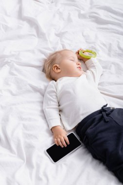 yüksek açılı çocuk çıngırak ile uyku ve evde boş ekran ile akıllı telefon