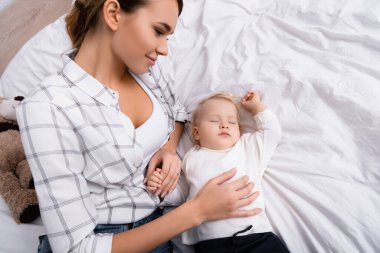 Uyuyan çocuğa dokunan gülümseyen kadın manzarası