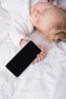 Uyuyan çocuğun elinde boş ekran olan cep telefonu.