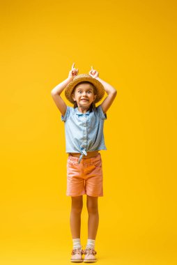 Hasır şapkalı, mutlu çocuk boyu sarıyı işaret ediyor.