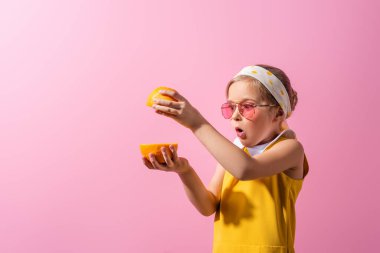 şaşırmış başörtüsü ve güneş gözlüğü takan pembe elbiseli bir kız. 