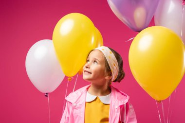 happy kid looking away near balloons isolated on crimson  clipart