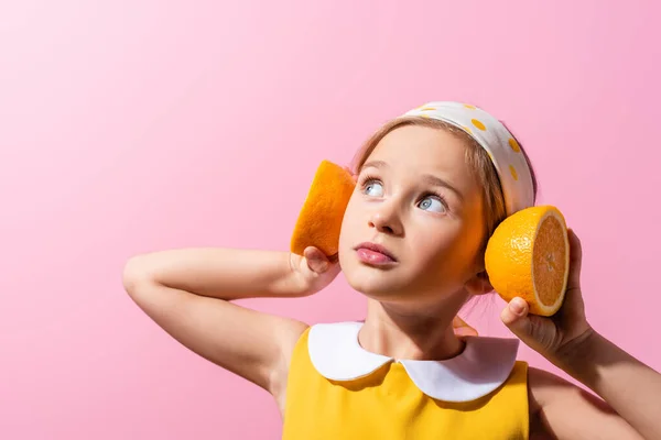 Mädchen Mit Kopftuch Hält Orangefarbene Hälften Ohrennähe Isoliert Auf Rosa — Stockfoto