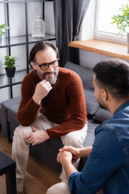 Gülümseyen bir adam oğluyla konuşurken ön planda bulanıklaşıyor.