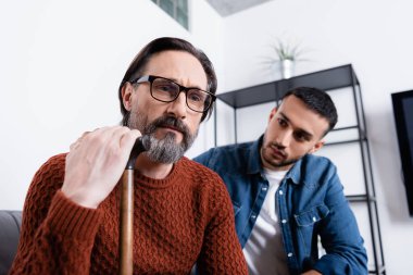 Bulanık arka planda genç İspanyol bir çocuğun yanında yürüyen depresif bir adam.