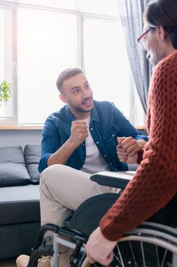 Heyecanlı İspanyol adam engelli babasının elini tutarken zafer işareti yapıyor.