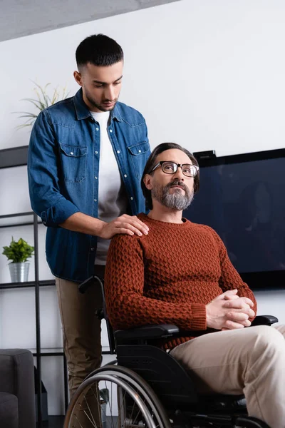 Jonge Spaanse Man Aanraken Schouder Van Bedachtzame Vader Zitten Een — Stockfoto