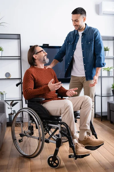 Happy Disabled Man Gesturing While Talking Smiling Hispanic Son Home — Stock Photo, Image