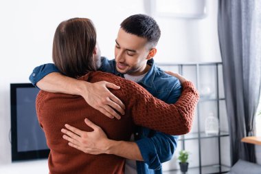 Genç İspanyol adam evde babasına sarılıyor.