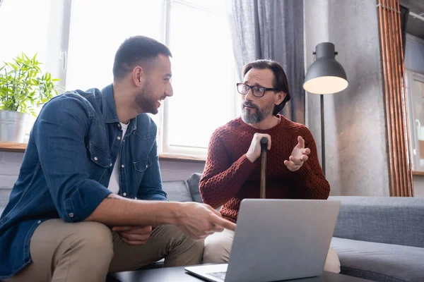 Uomo Stupito Guardando Sorridente Figlio Ispanico Che Punta Computer Portatile — Foto Stock