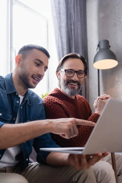 Smiling Hispanic Man Pointing Laptop Cheerful Father Blurred Foreground — Stock Photo, Image