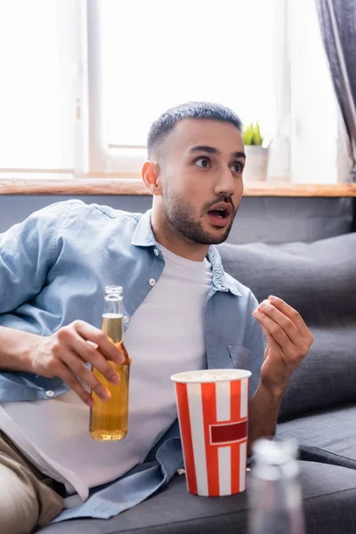 Amazed Hispanic Man Bottle Beer Watching Eating Popcorn Home Blurred — Stock Photo, Image