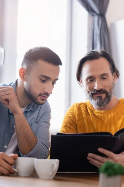 Smiling Bearded Man Young Hispanic Son Looking Photo Album Blurred — Stock Photo, Image