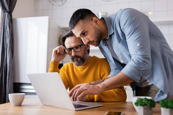 Junger Hispanischer Mann Tippt Auf Laptop Neben Nachdenklichem Vater Der — Stockfoto