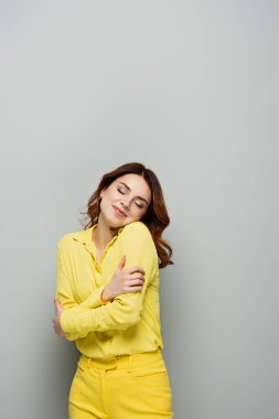 Mutlu, hayalperest kadın griye kapalı gözlerle bakarken kendine sarılıyor.